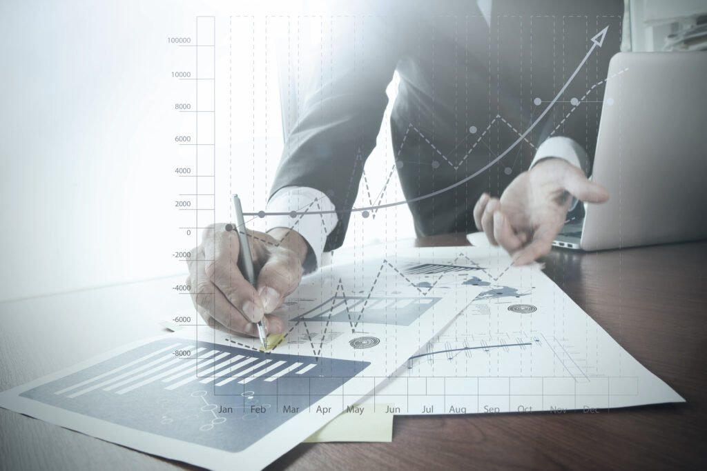 Close-up of a hand working on a laptop with business graphs on the screen