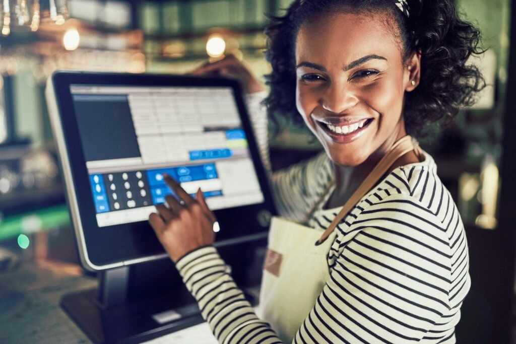 Smiling restaurant server using a touchscreen point-of-sale terminal