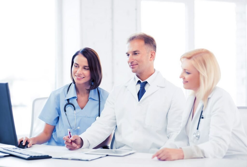 Three clinicians reviewing software on a desktop computer together at an office desk