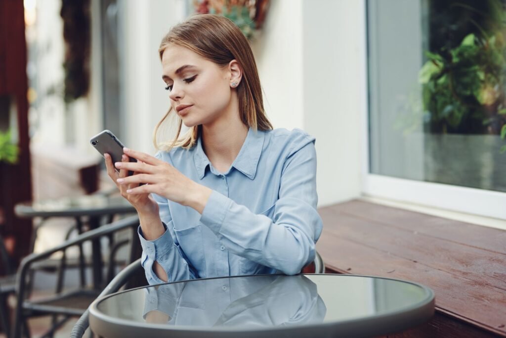 Young woman checking her phone at an outdoor cafe table