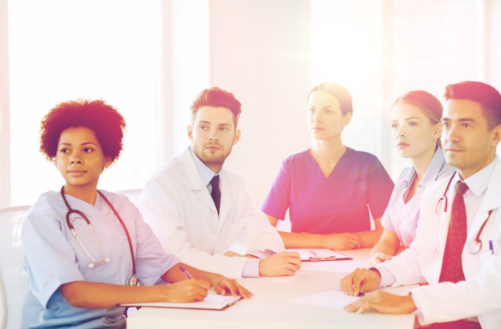 Doctors and nurses seated at a conference table during a hospital meeting