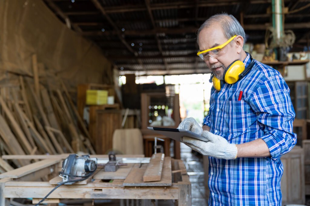 Senior carpenter checking a digital tablet in his woodworking shop