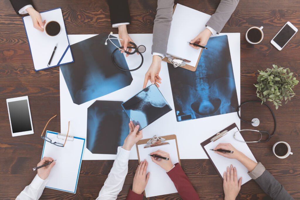 Top view of people reviewing x-ray films and taking notes at a desk